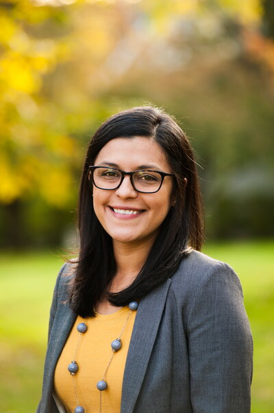 Dr. Stephanie Mota Thurston standing in front of fall folliage